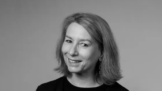 A black and white portrait of a middle-aged woman smiling slightly at the camera, with shoulder-length hair and earrings.