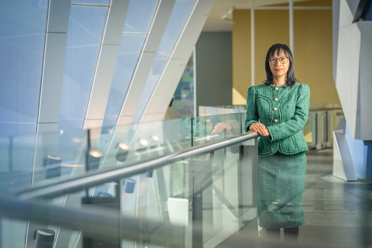 Nhung Nghiem is standing next to a balustrade in an office building.