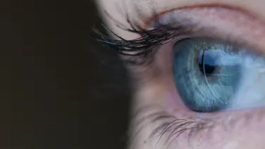 Close-up image of a human eye, highlighting detailed eyelashes and a clear, blue iris.